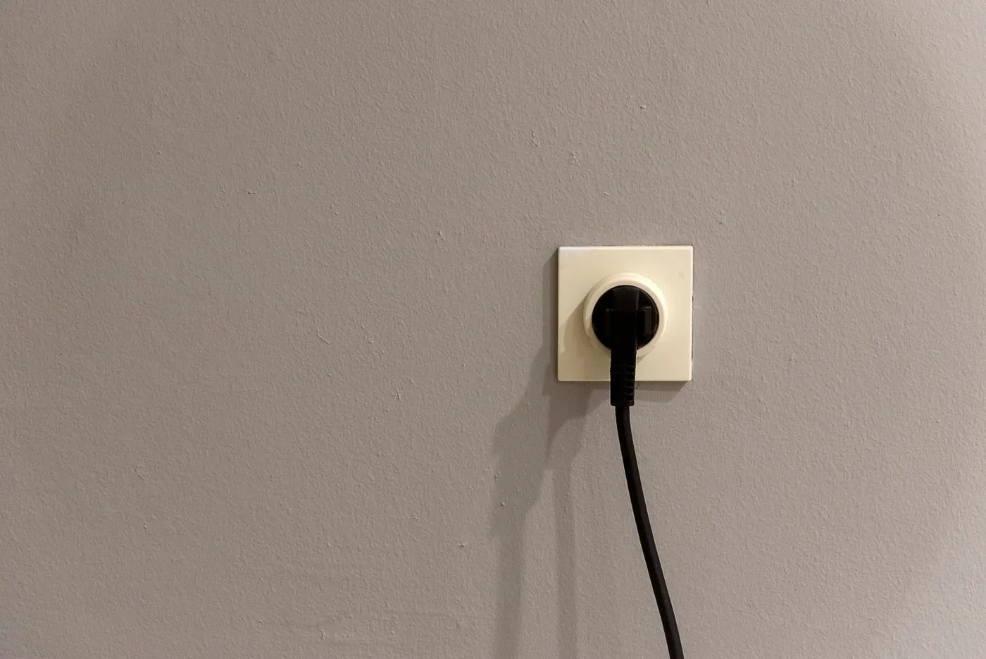 壁のコンセントに黒い電源プラグが1本だけ差し込まれている